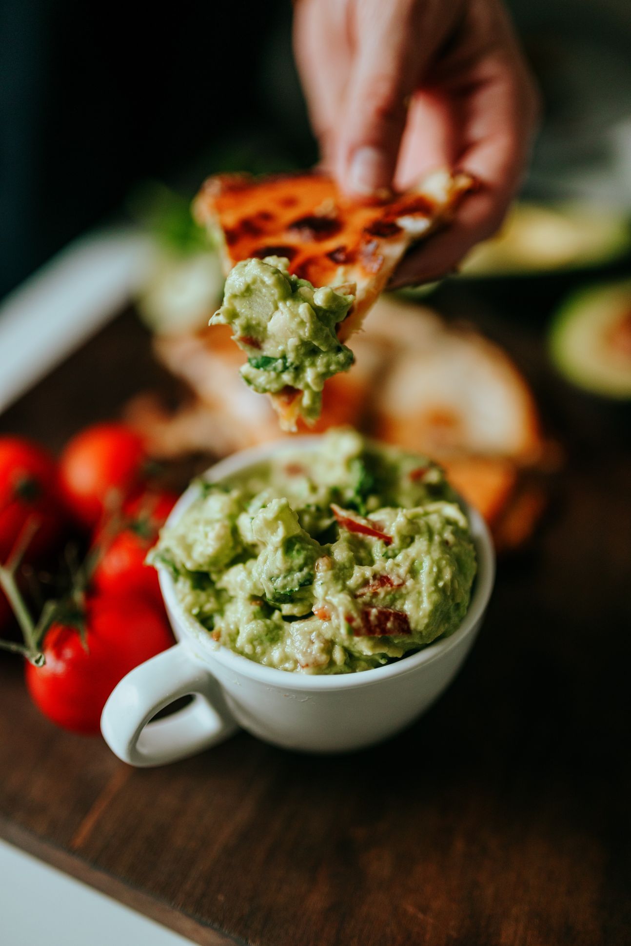 Avocado-Aufstrich in einer Tasse, drumherum bunte Dekoration.