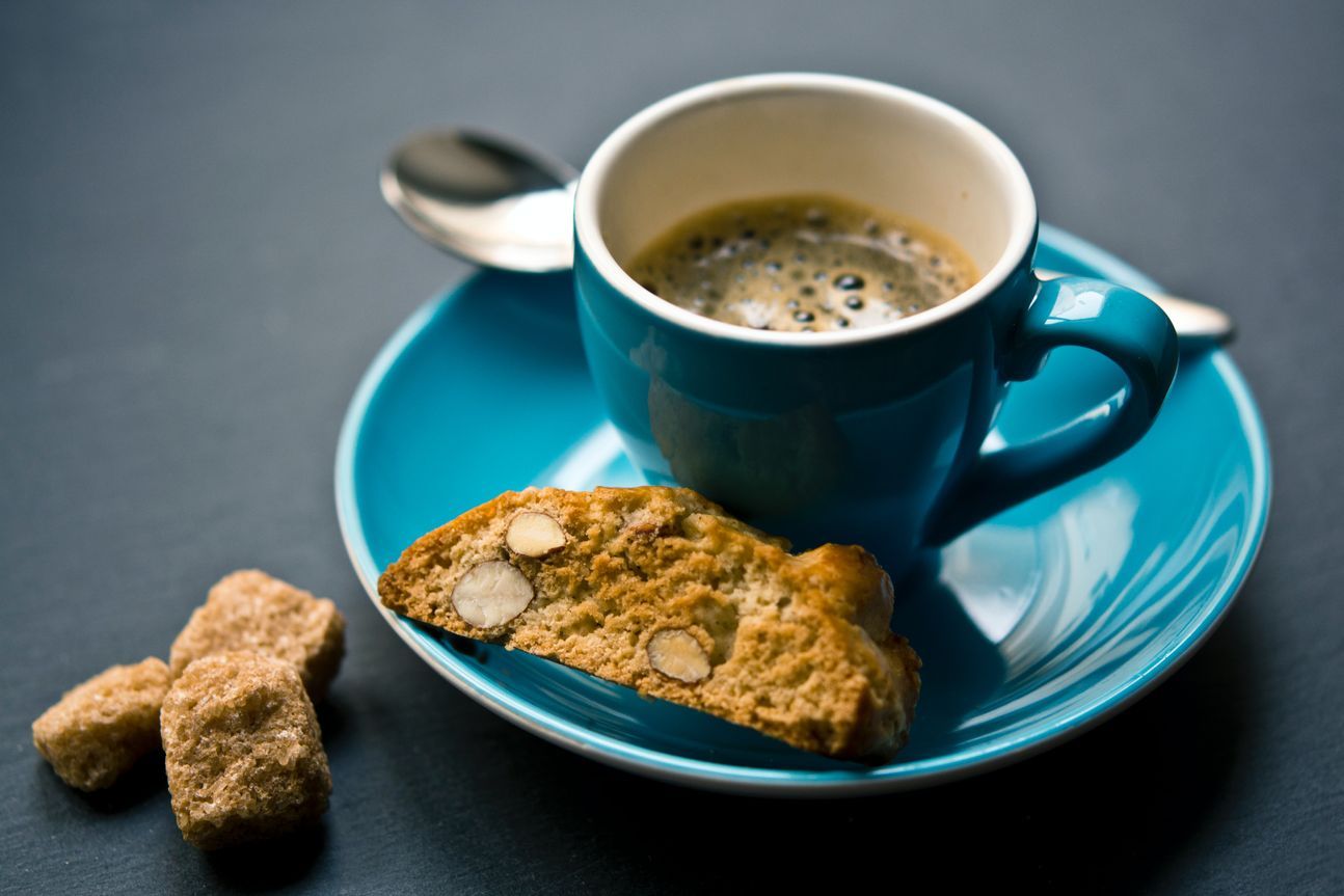 Eine blaue Tasse mit Espresso, dazu Biscotti.