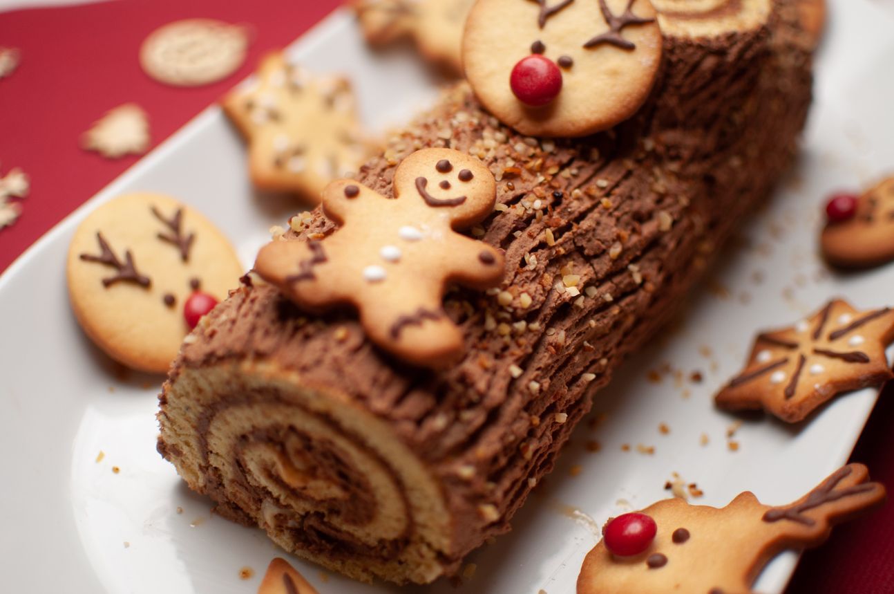 Ein schokoladiger, angeschnittener Bûche de Noël, verziert mit Buttergebäck.