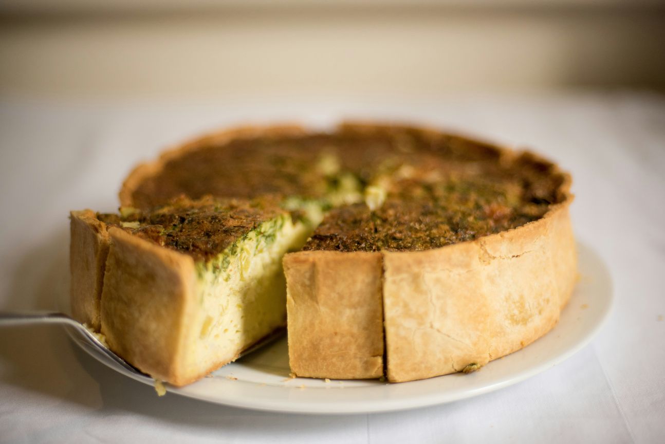 Quiche auf einem Teller. Ein Stück abgeschnitten.