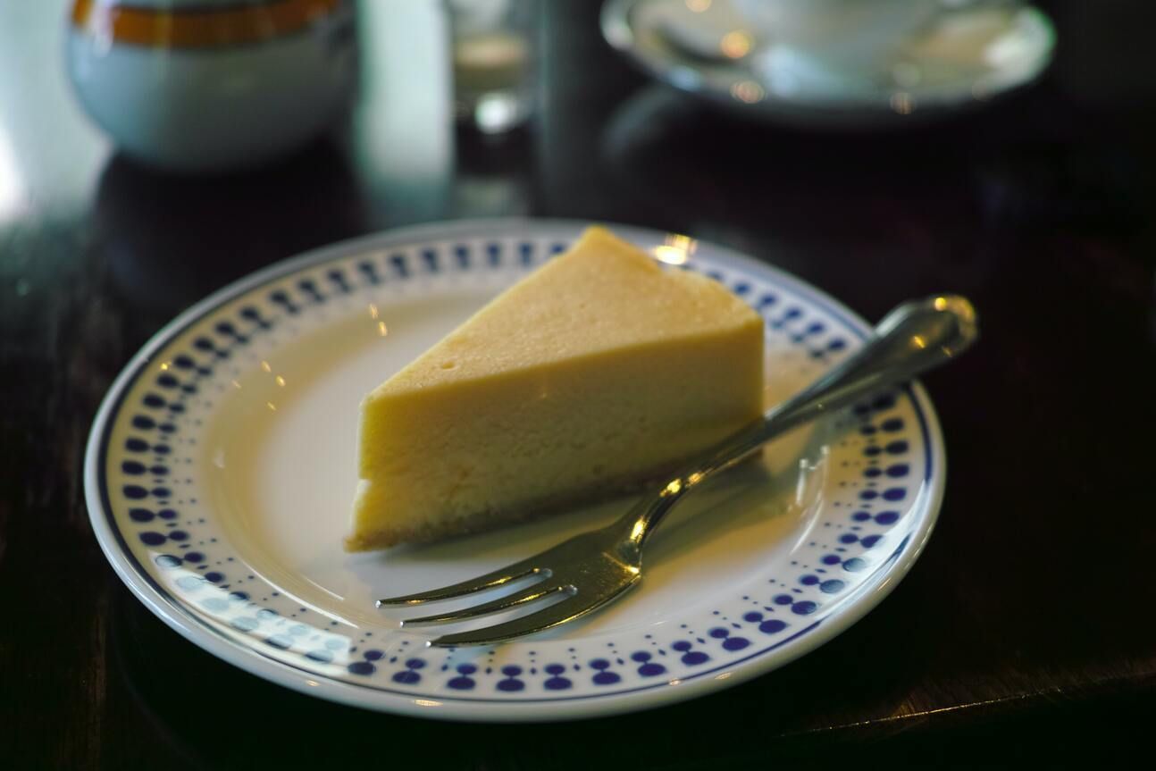 Ein Stück Käse-Kokos-Kuchen auf einem Teller mit Gabel.