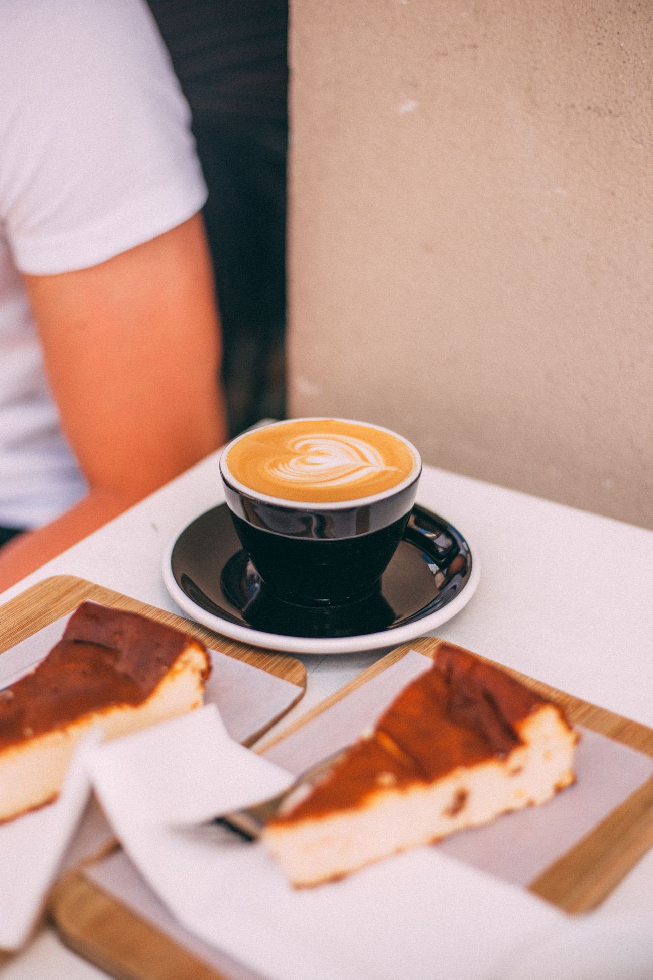 Zwei Stück Käsekuchen mit einer Tasse Heißgetränk serviert.