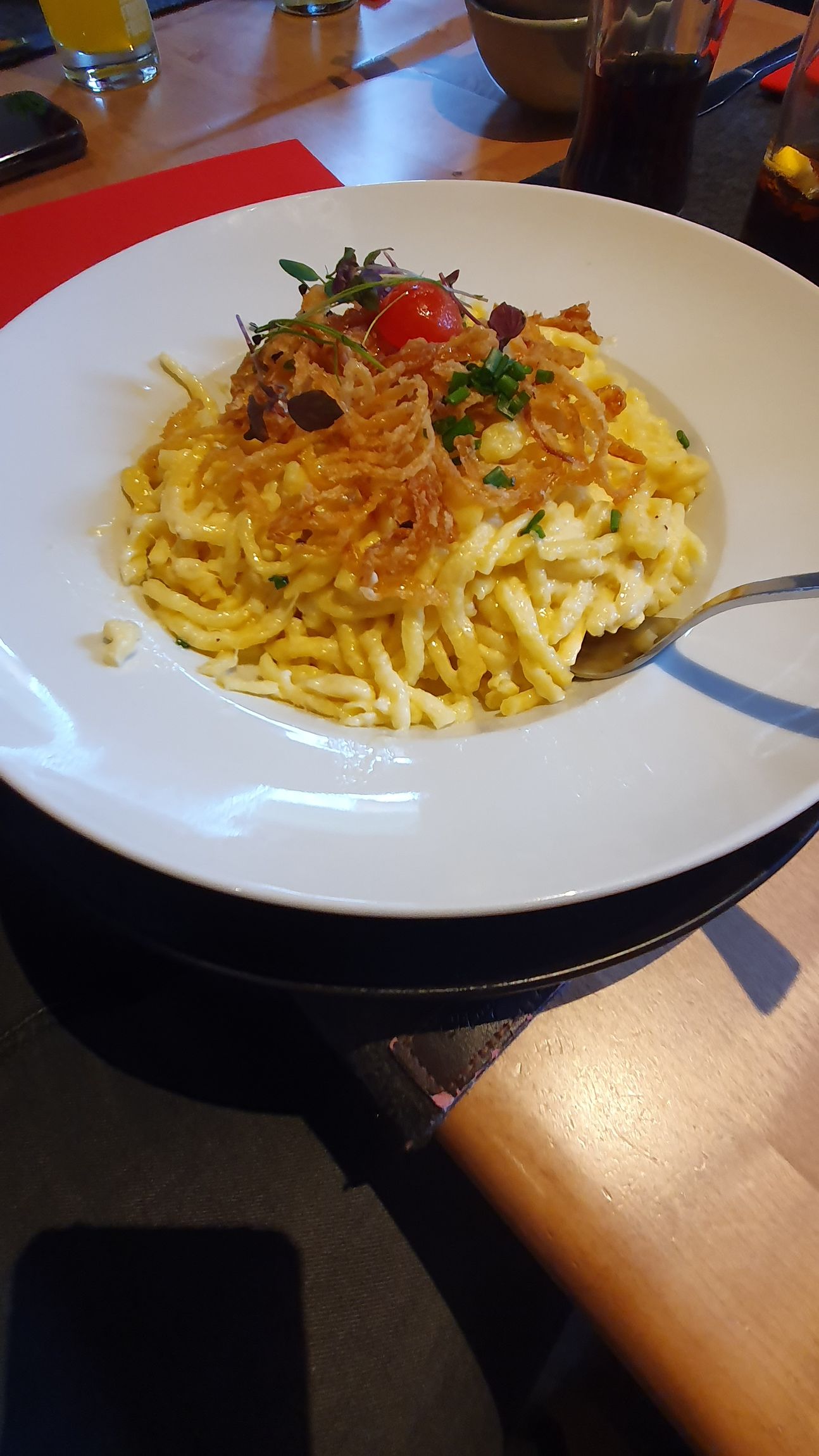 weißer Teller mit Käsespätzle und Röstzwiebeln