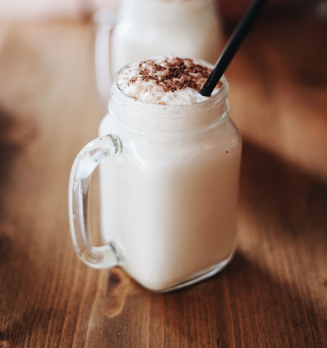 Ein Glas mit Henkel, darin weiße Flüssigkeit und Schoko obendrauf.