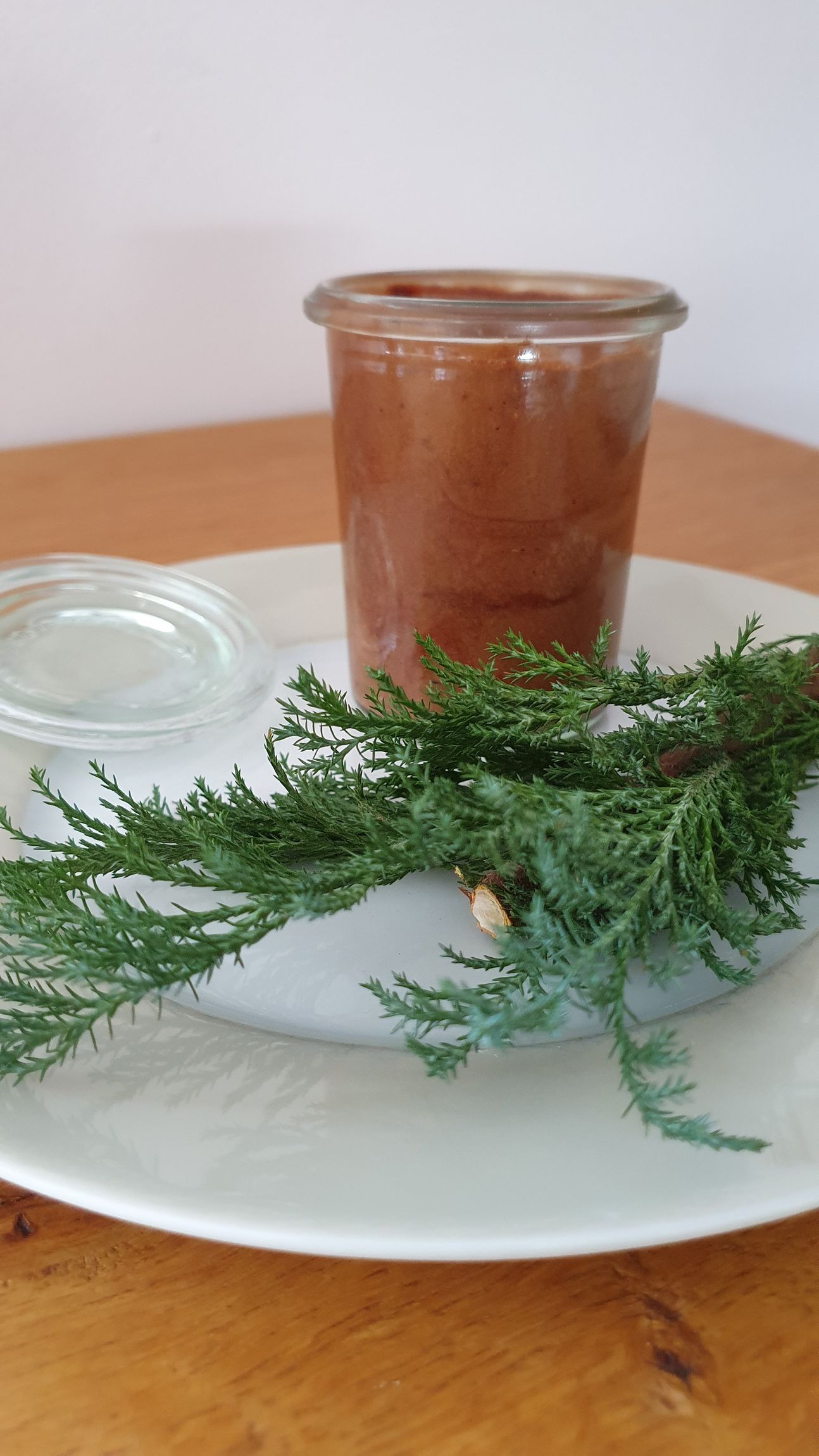 Eine Mousse au chocolat in einem Weck-Gläschen, das auf einem weißen Teller mit Zweig dekoriert ist.