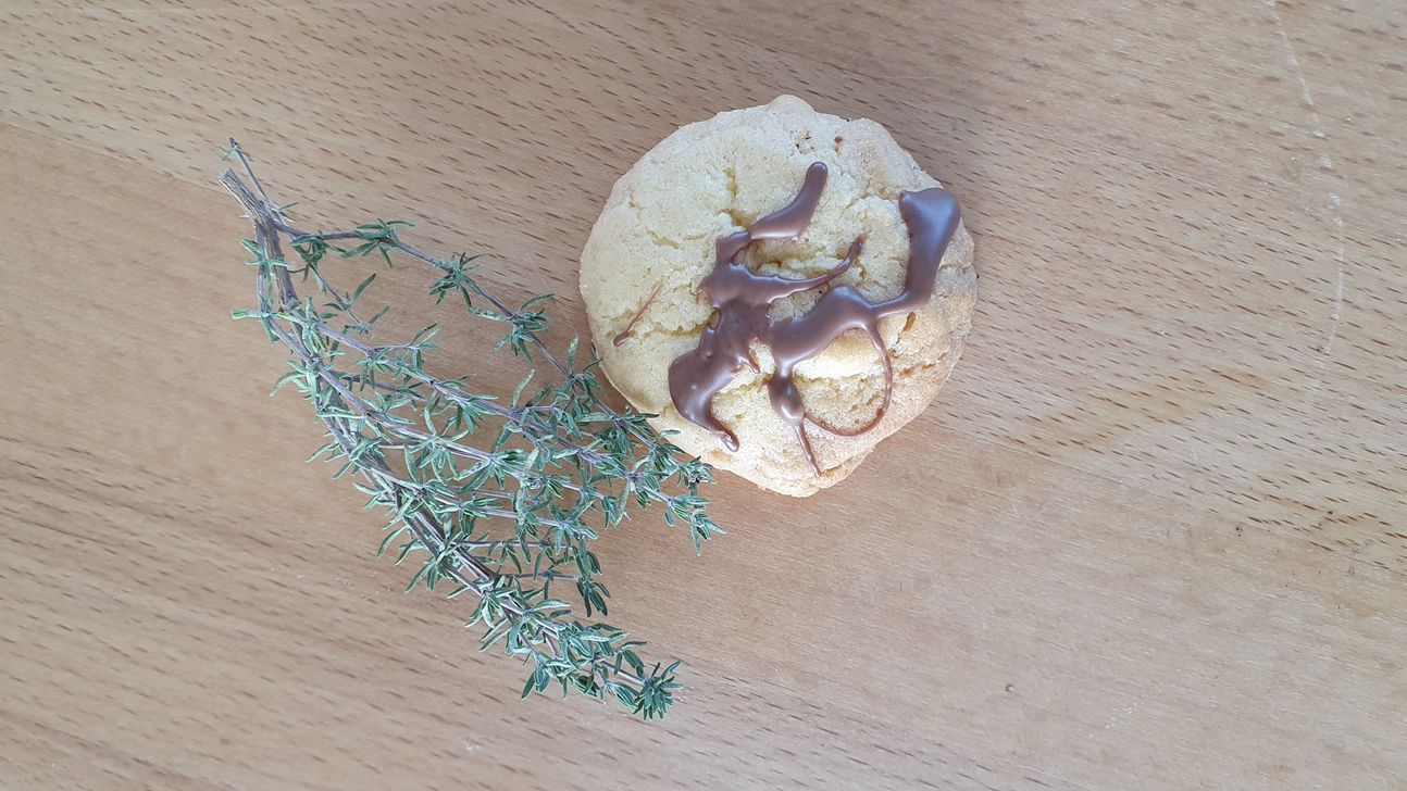 Plätzchen, dekoriert mit flüssiger Schokolade auf einem weißen Teller.