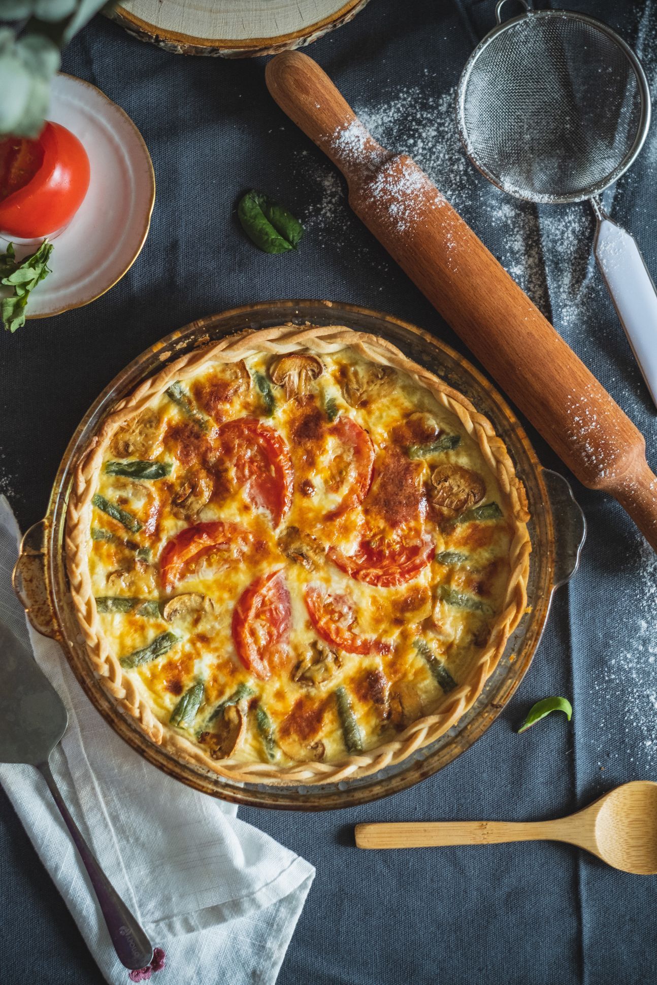 Eine Tomaten-Zucchini-Quiche, schön dekoriert auf einem Tuch.