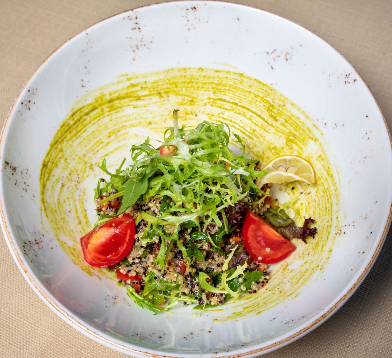 Weißer Teller mit Salat und Dressing.