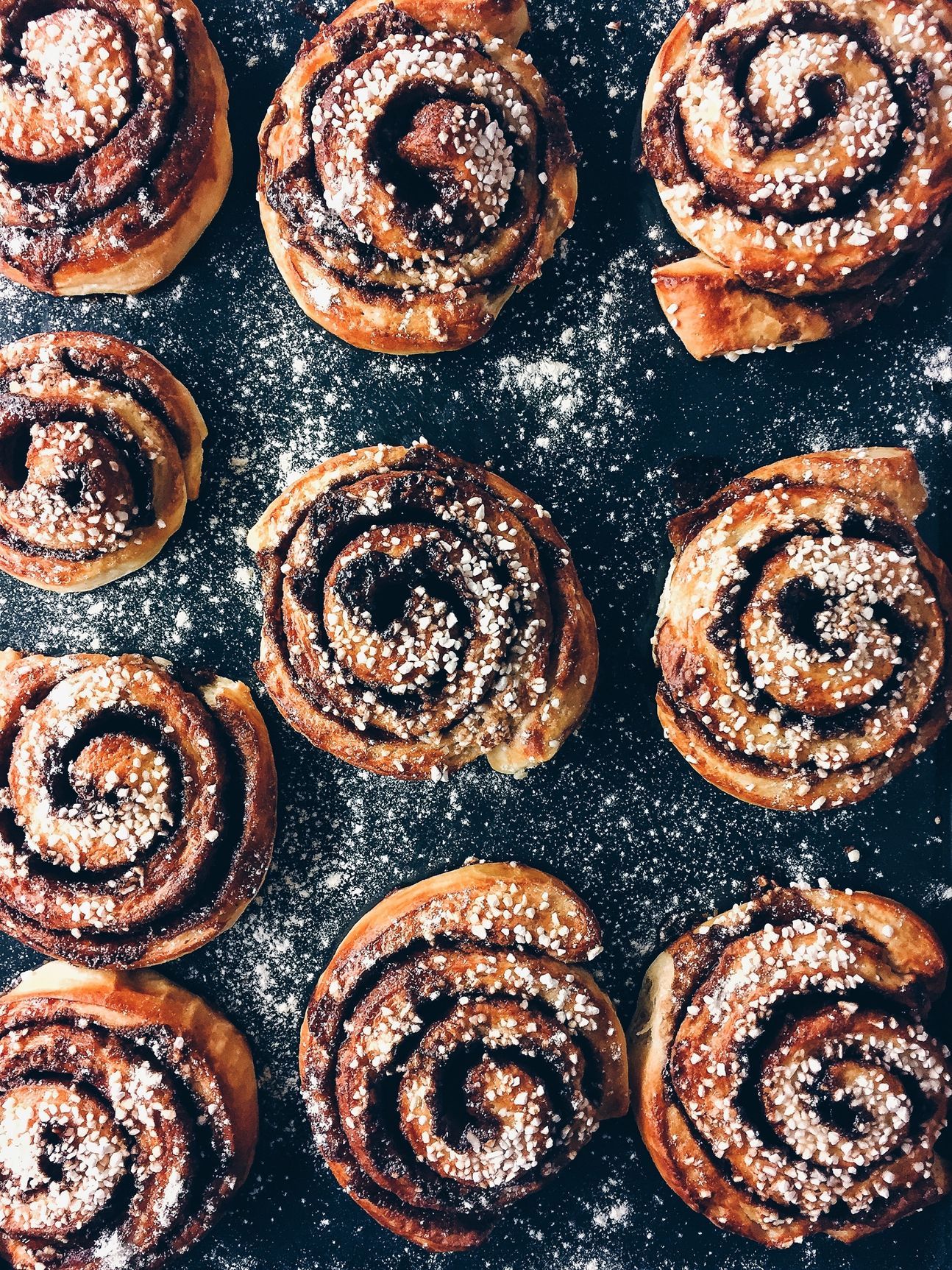 Mehrere Hefe-Schnecken, die gefüllt sind und nebeneinander in 3 Reihen liegen.