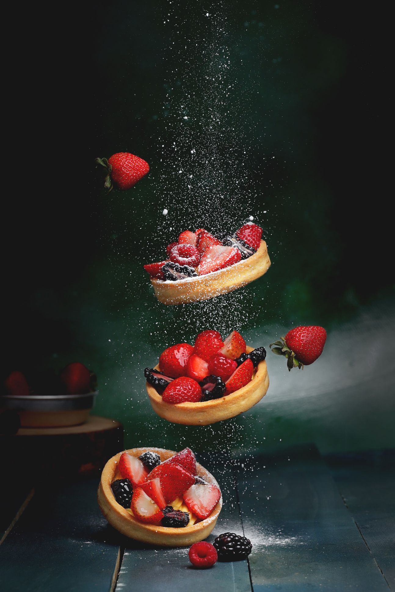 Mehrere Tartelettes mit verschiedenen Beeren schweben in der Luft.