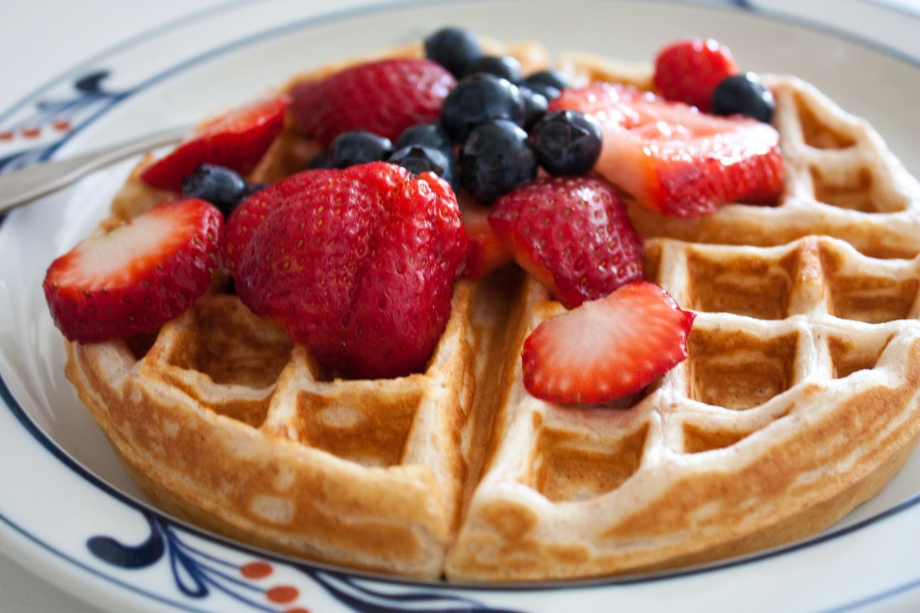 Eine runde Waffeln mit Erd- und Heidelbeeren auf einem Teller.