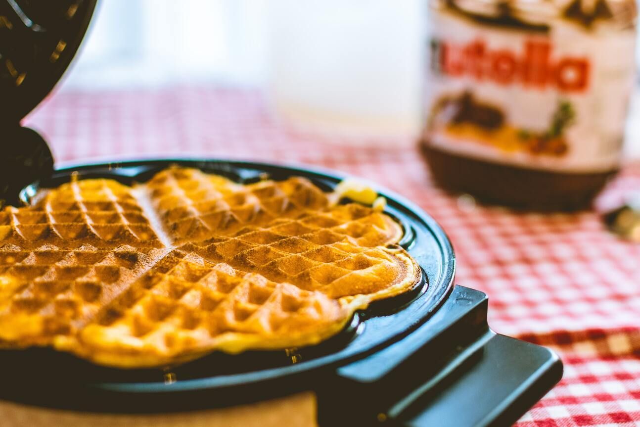 Ein rundes Waffeleisen mit einer fertig gebackenen Waffel.